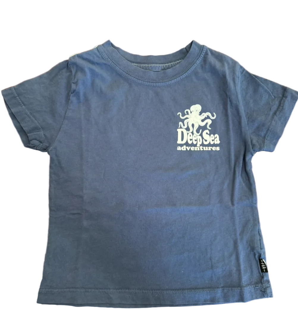 Blue t-shirt with 'Deep Sea Adventures' logo on a wooden surface